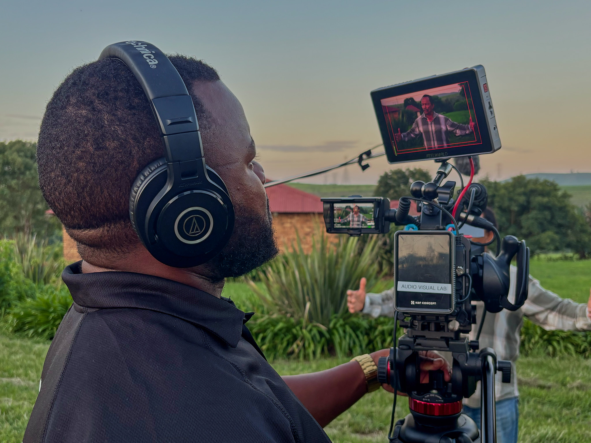 Videographer operating cinema camera on location — golden hour